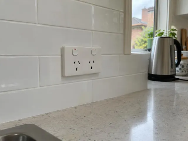 Double power point on white tiled kitchen splashback beside a benchtop and window in Roseville